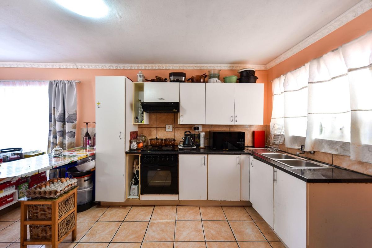 A functional kitchen featuring white cabinetry, a built-in oven with hob, double sink, and tiled flooring, offering potential for a modern renovation.