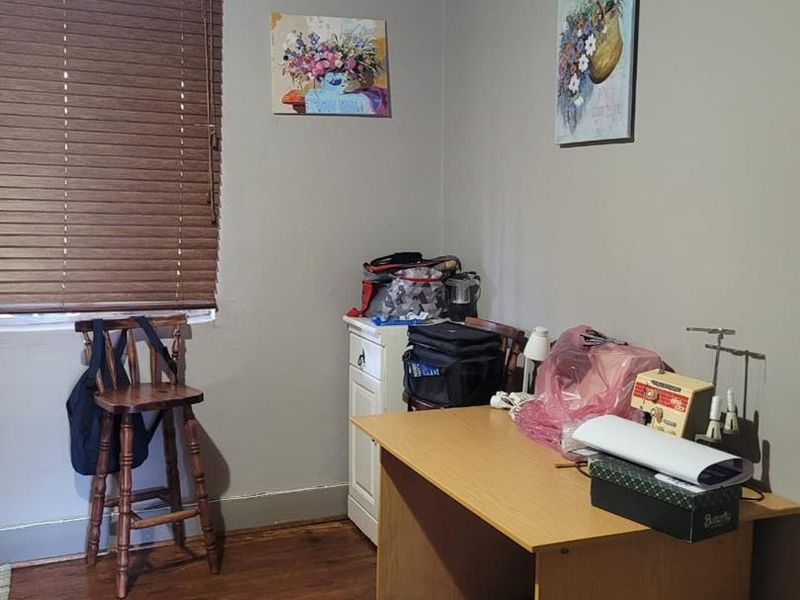 A bedroom featuring timber flooring and venetian blinds, currently utilized as a workspace.