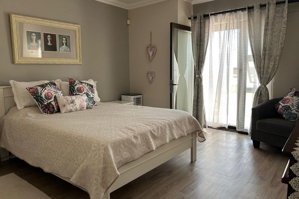 A well-maintained bedroom featuring wood-look laminate flooring, neutral wall tones, and a glass door providing access to an outdoor area.