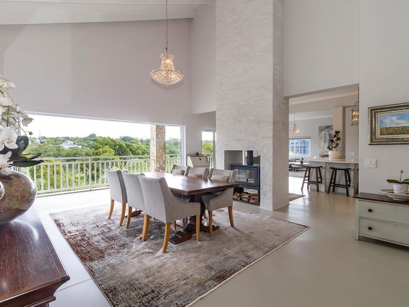 Spacious open-plan dining area featuring a double-sided stone fireplace, high vaulted ceilings, and seamless access to a covered balcony with scenic views.