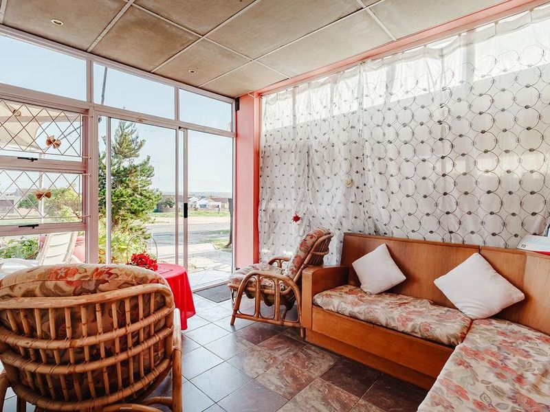 Enclosed sunroom or patio area featuring tiled flooring, large sliding glass doors, and security bars, offering a bright space with potential for modernization.
