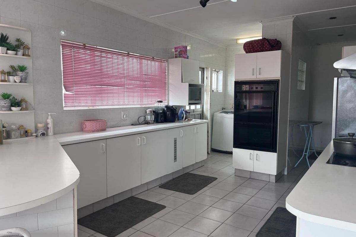 A functional kitchen featuring white cabinetry, tiled surfaces, built-in double oven, and track lighting, offering a clean and practical workspace.