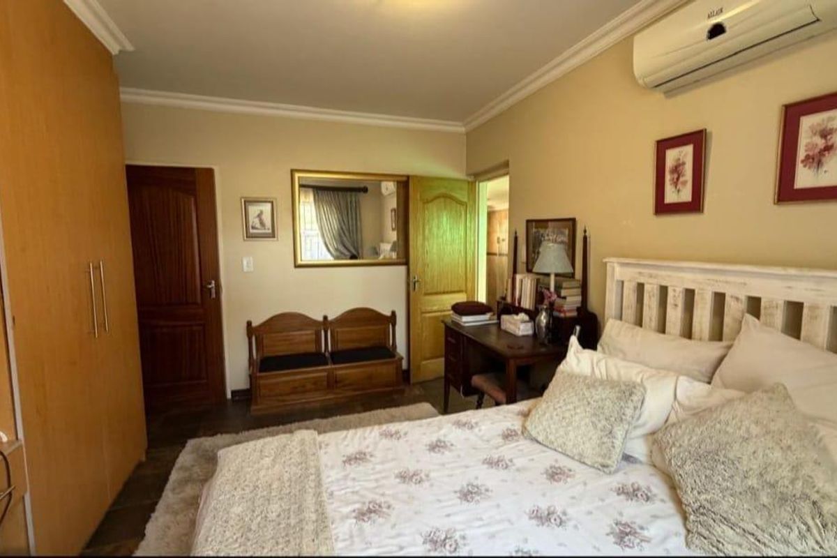 A well-maintained bedroom featuring built-in wooden cabinetry, crown molding, and a wall-mounted air conditioning unit.