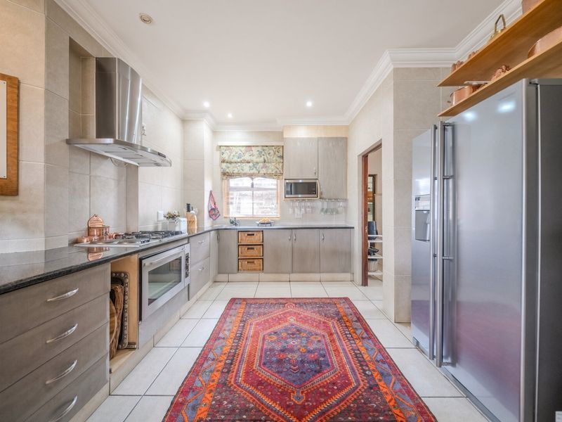 A well-maintained kitchen featuring granite countertops, stainless steel appliances, built-in cabinetry, and tiled flooring with recessed lighting.