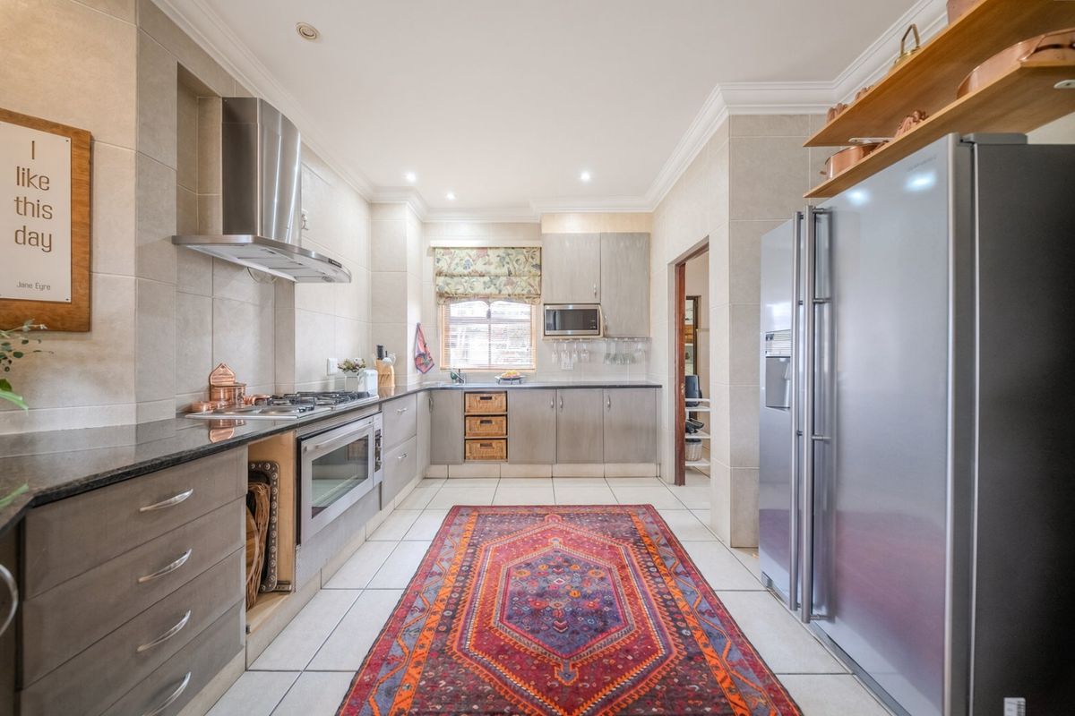 A well-maintained kitchen featuring granite countertops, stainless steel appliances, built-in cabinetry, and tiled flooring with recessed lighting.