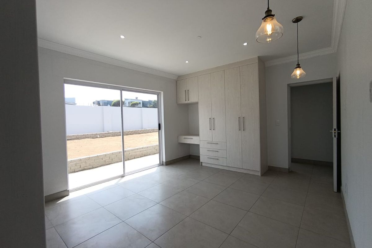 A bright bedroom featuring built-in cabinetry with an integrated desk, tiled flooring, and sliding glass doors leading to an outdoor area.