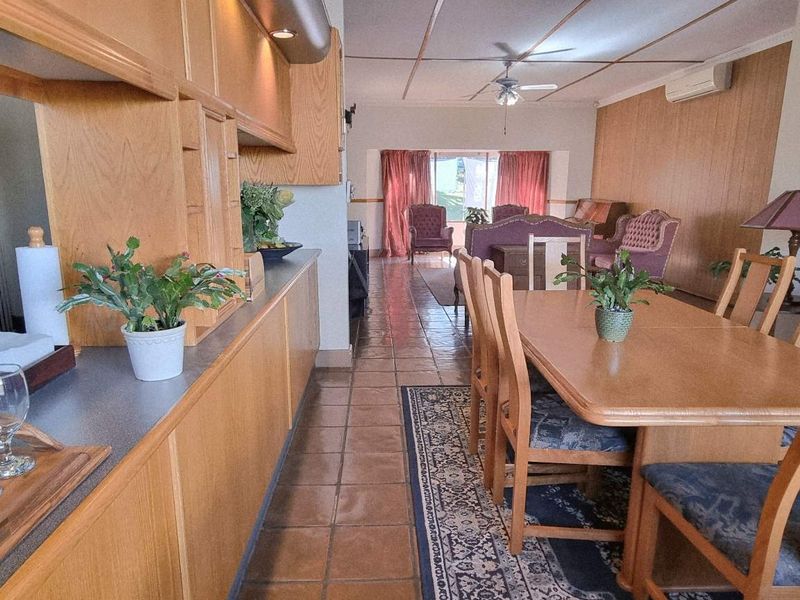 Open-plan living and dining area featuring tiled flooring, built-in cabinetry, and wood-paneled walls, offering a functional layout with potential for modern updates.