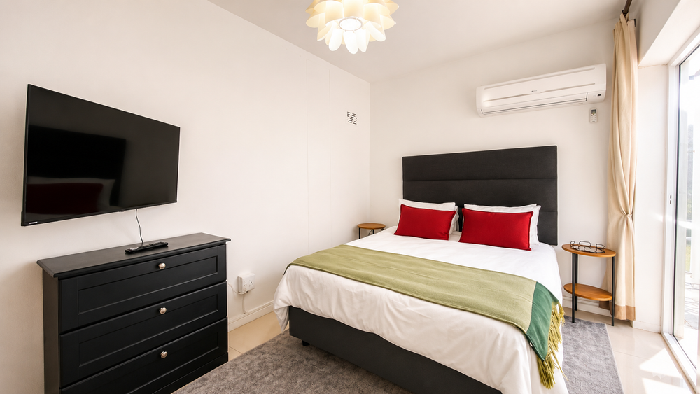 Bright, furnished bedroom with aircon and TV