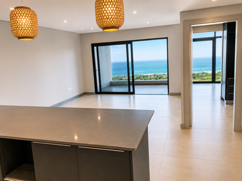 Modern open-plan living area featuring a kitchen island, neutral tiled flooring, and expansive sliding doors opening to a scenic ocean view.