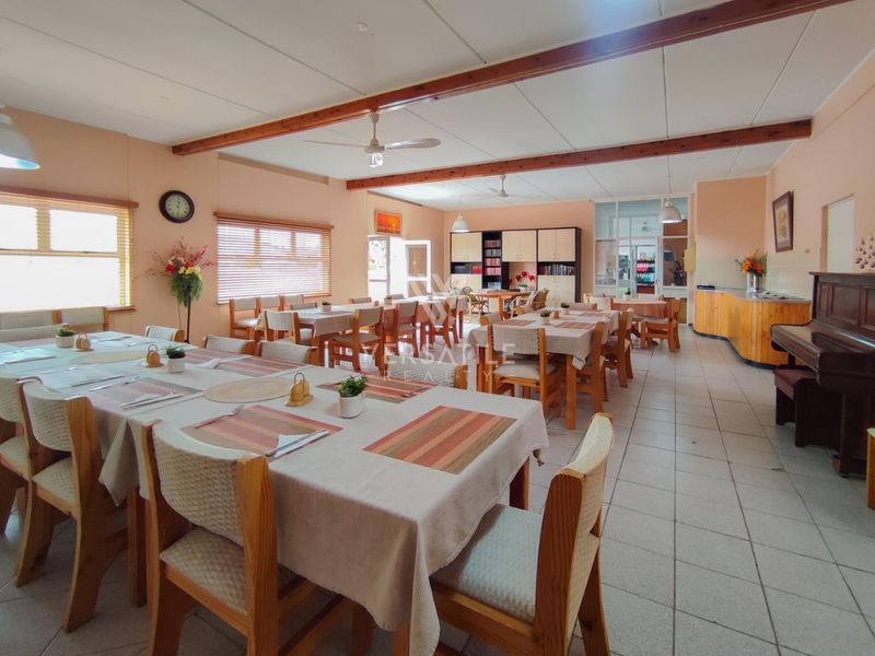 Spacious communal dining area featuring tiled flooring, exposed timber ceiling beams, ceiling fans, and built-in storage cabinetry.
