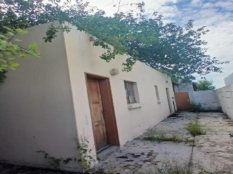 Rear exterior view of the industrial property featuring a paved yard area enclosed by a concrete boundary wall with visible signs of weathering.