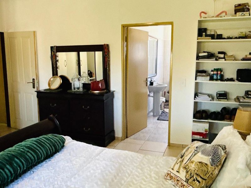 A bedroom featuring tiled flooring, built-in wardrobe storage, and direct access to an en-suite bathroom.