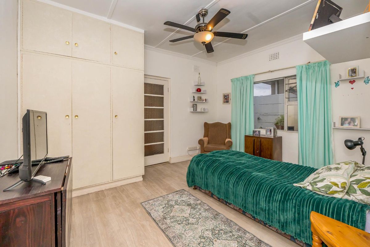 A bedroom featuring built-in floor-to-ceiling cupboards, a ceiling fan, and light-toned flooring.