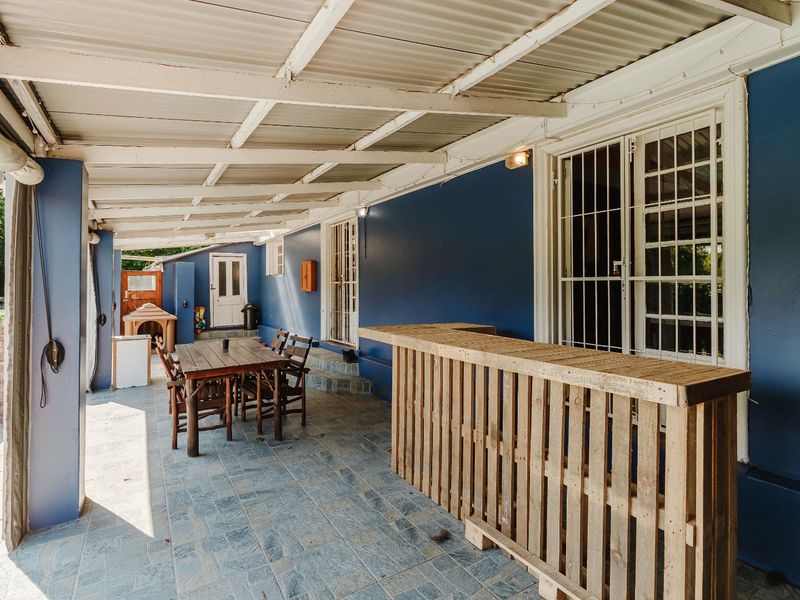 Covered outdoor patio area featuring tiled flooring, corrugated roofing, and direct access to the home, providing a functional space for outdoor entertaining.