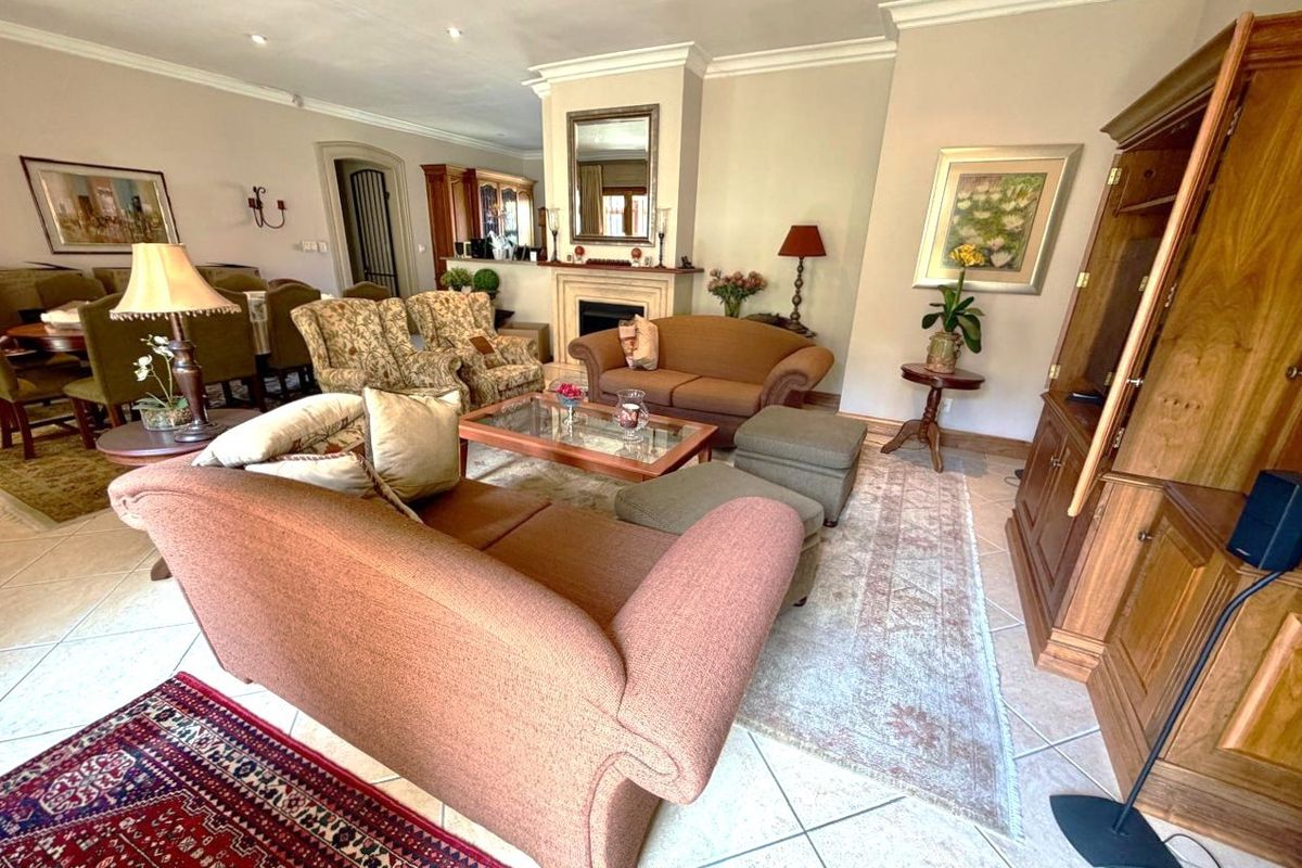 Spacious living room featuring a central fireplace with mantelpiece, tiled flooring, and elegant crown molding, creating a comfortable and traditional atmosphere.