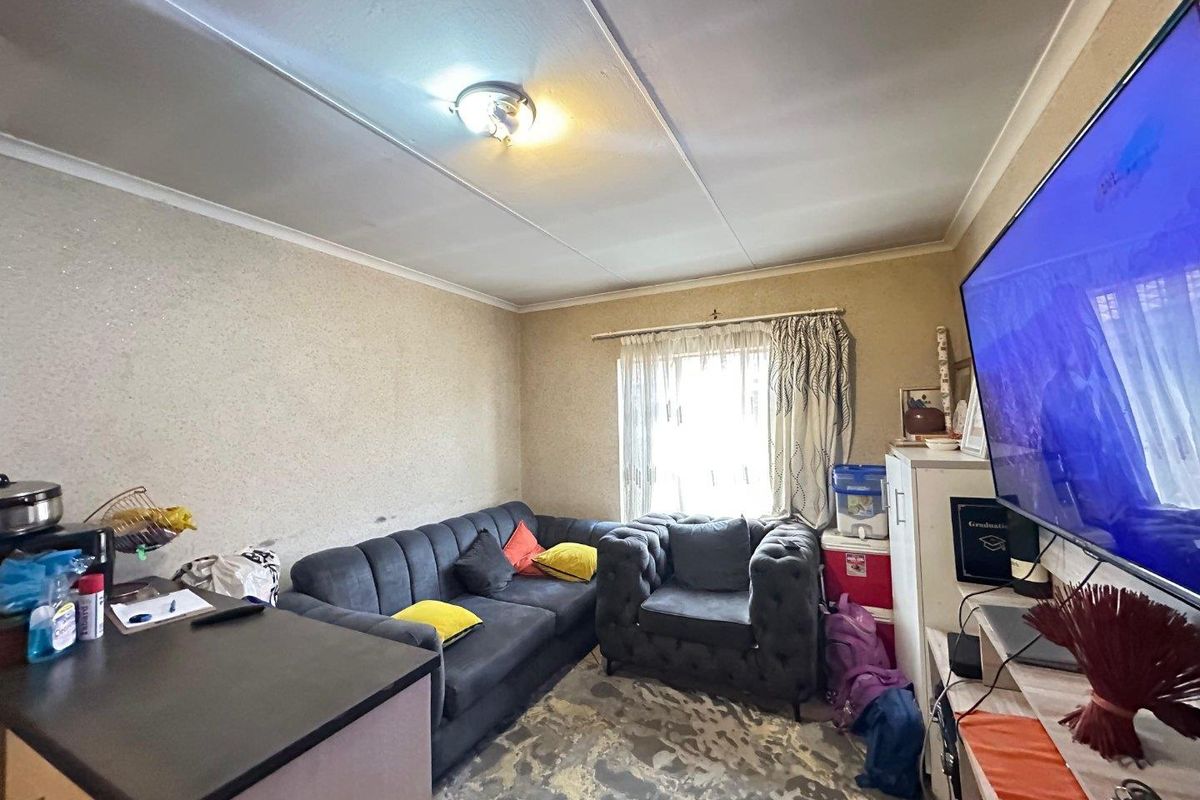 A compact living room area featuring a window with natural light, standard ceiling finishes, and neutral wall textures.