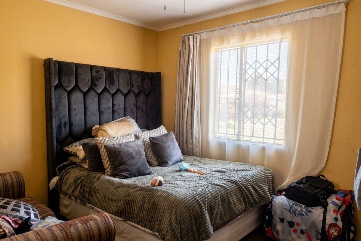 A bedroom featuring a ceiling fan and a window fitted with a security gate, providing natural light and ventilation.