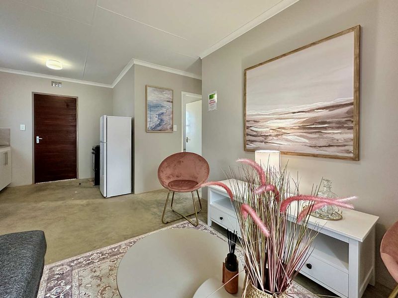 Open plan living area featuring neutral wall tones, cove cornicing, and tiled flooring, providing a functional and versatile space.