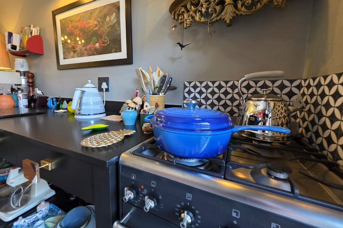 A close-up view of a kitchen workspace featuring a built-in gas stove, dark countertops, and a decorative patterned tile backsplash.