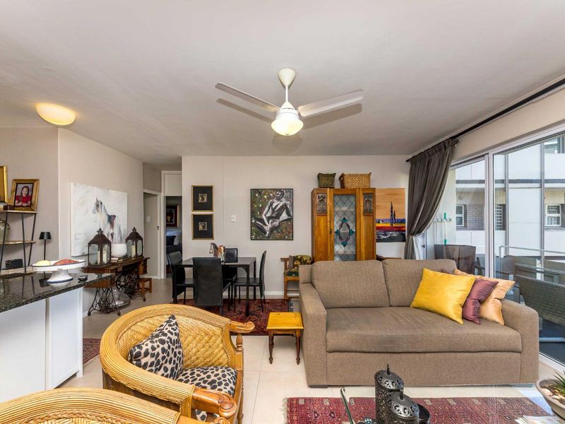 Open-plan living and dining area featuring tiled floors, a ceiling fan, and large sliding glass doors leading to an outdoor balcony space.