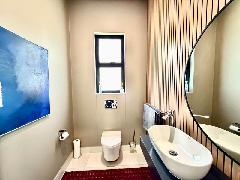 Modern guest bathroom featuring a wall-mounted toilet, stylish vessel sink, and contemporary slatted timber wall paneling.