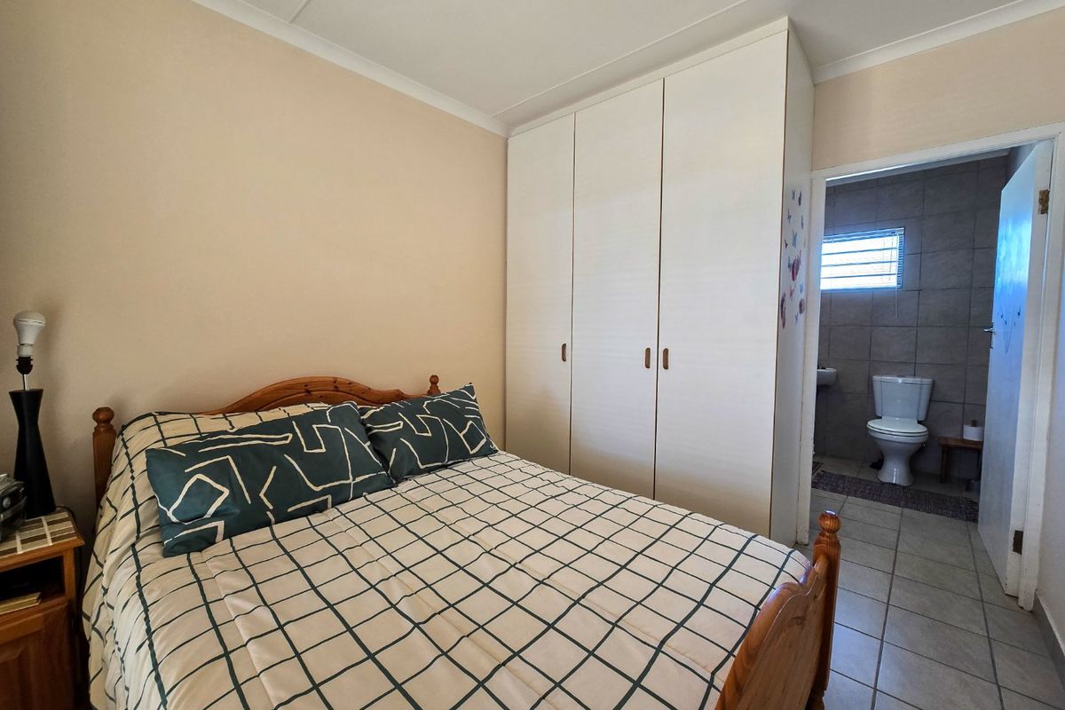 A bedroom featuring built-in wardrobes, tiled flooring, and direct access to an en-suite bathroom.