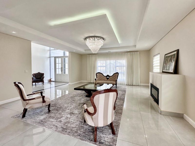 Spacious living room featuring polished tile flooring, a modern recessed ceiling with ambient lighting, and a built-in fireplace.
