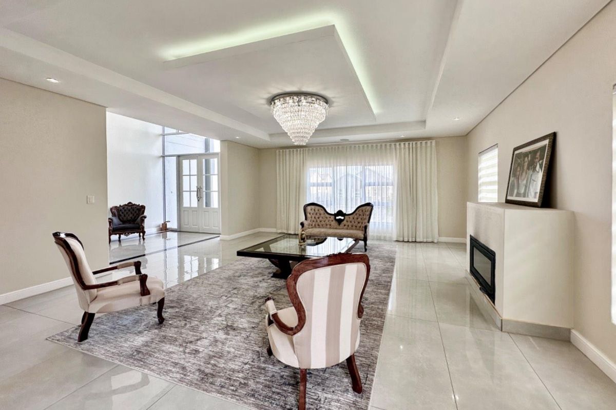 Spacious living room featuring polished tile flooring, a modern recessed ceiling with ambient lighting, and a built-in fireplace.