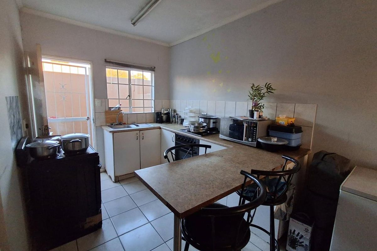 A functional kitchen featuring tiled flooring, a tiled backsplash, built-in cabinetry, and a breakfast counter area with direct access to the exterior.