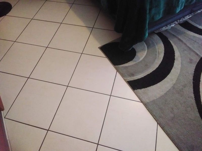 A close-up view of white ceramic floor tiles with dark grout lines.