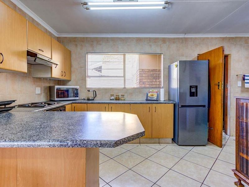 A functional kitchen featuring light wood cabinetry, granite countertops, tiled backsplash, and tiled flooring, offering a practical layout for daily meal preparation.
