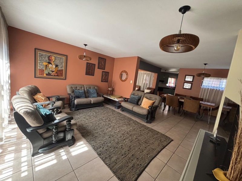 Spacious open-plan living and dining area featuring neutral tiled flooring and warm-toned walls, providing a versatile layout for family living and entertaining.