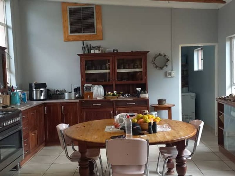 A spacious kitchen featuring warm wooden cabinetry, a gas stove with extractor fan, tiled flooring, and a dedicated dining area.