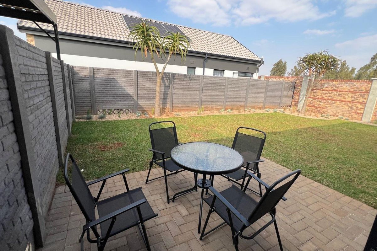 A private rear garden featuring a paved patio area, well-maintained lawn, and secure perimeter walling, ideal for outdoor relaxation.