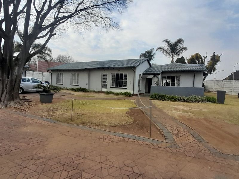 Front view of a single-story residential house featuring a tiled roof, paved driveway, and attached garage with a surrounding garden area.
