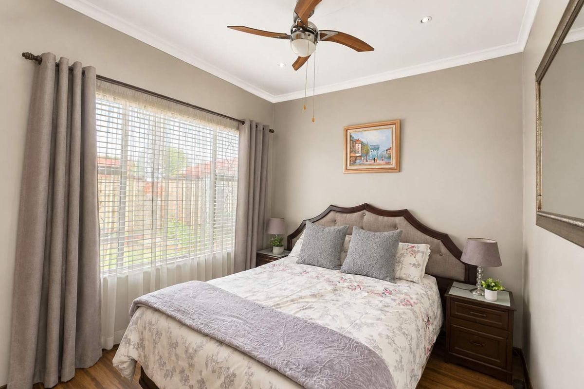 A well-maintained bedroom featuring laminate flooring, recessed ceiling lighting, and a central ceiling fan, offering a comfortable and neutral living space.