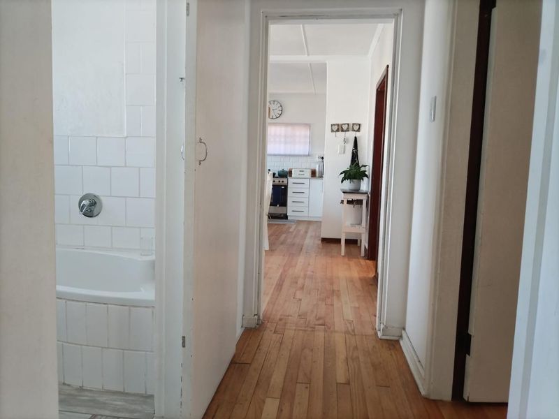 A view from the hallway looking towards the kitchen, featuring hardwood flooring and a glimpse into an adjacent tiled bathroom.
