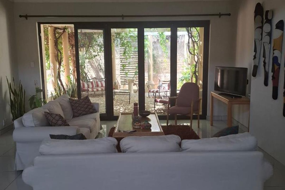 Spacious living room featuring large glass sliding doors that open onto a private patio and garden area, providing ample natural light.