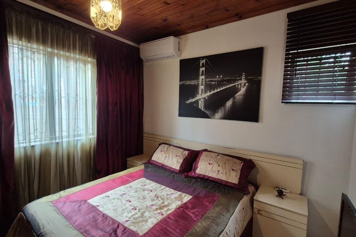A bedroom featuring a timber-paneled ceiling, a wall-mounted split-system air conditioner, and integrated built-in headboard and bedside cabinetry.