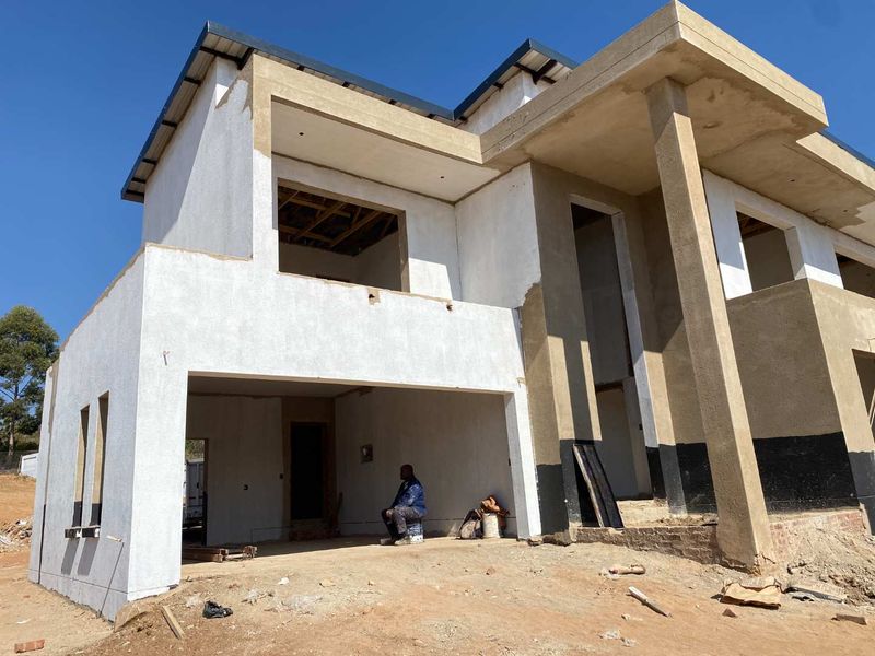 A double-storey residential property currently under construction, featuring a plastered facade, concrete columns, and an incomplete exterior structure.