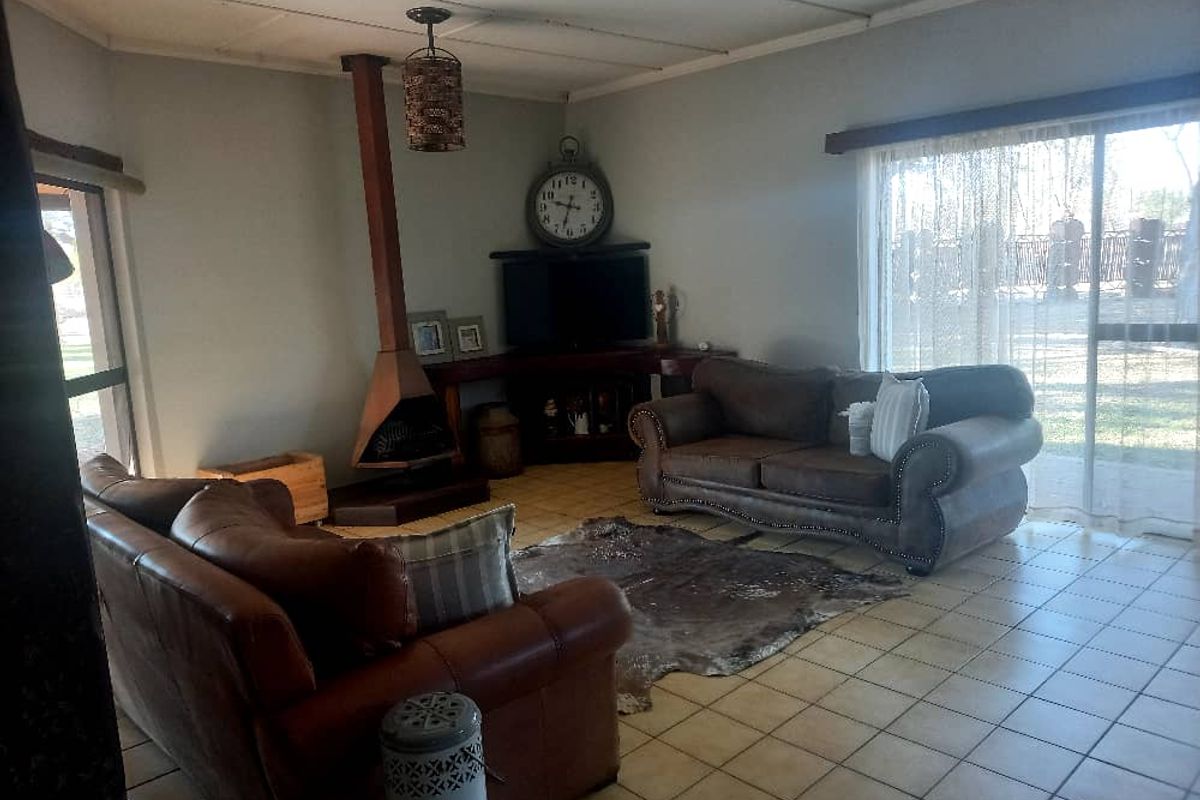 Spacious living room featuring a suspended fireplace, tiled flooring, and large sliding glass doors providing natural light and garden access.