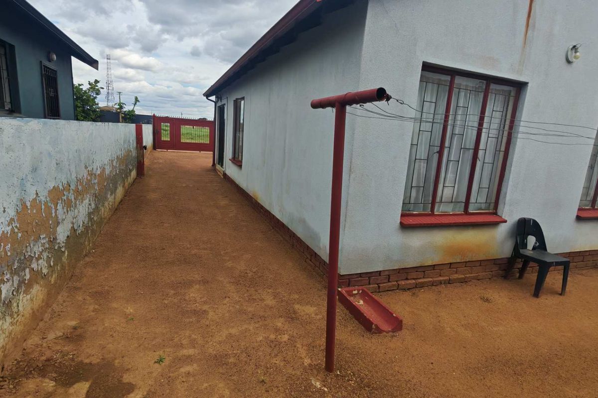 Side exterior view of the property featuring a perimeter wall, metal window frames, and a fixed washing line area.