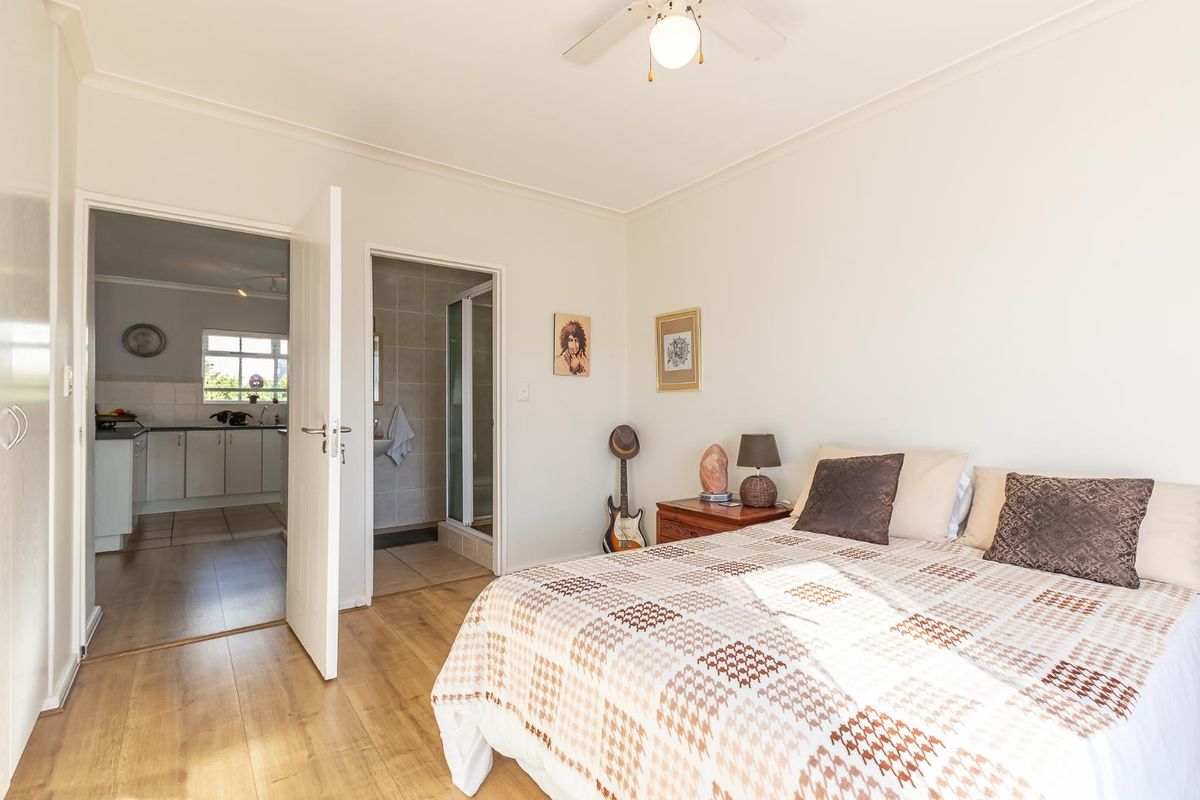 A well-lit bedroom featuring laminate flooring, a ceiling fan, and direct access to an en-suite bathroom.