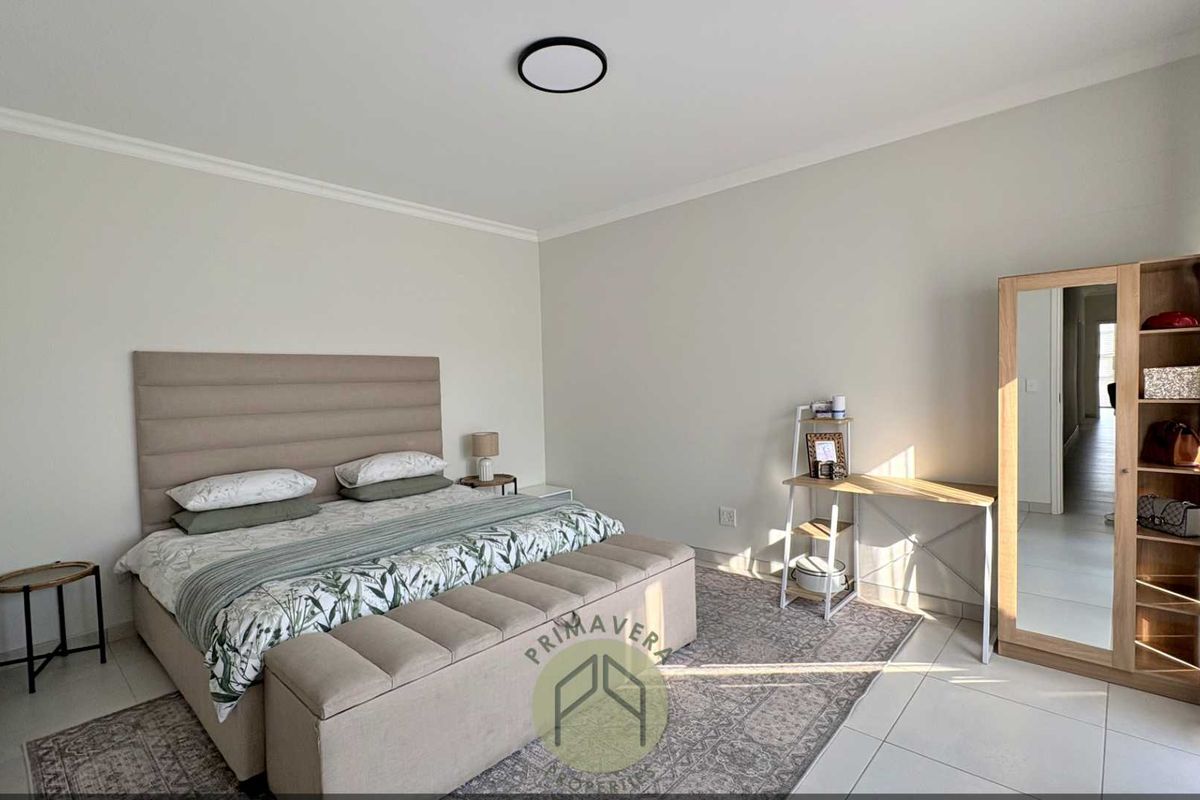 A well-maintained bedroom featuring neutral wall tones, tiled flooring, and a modern ceiling light fixture.