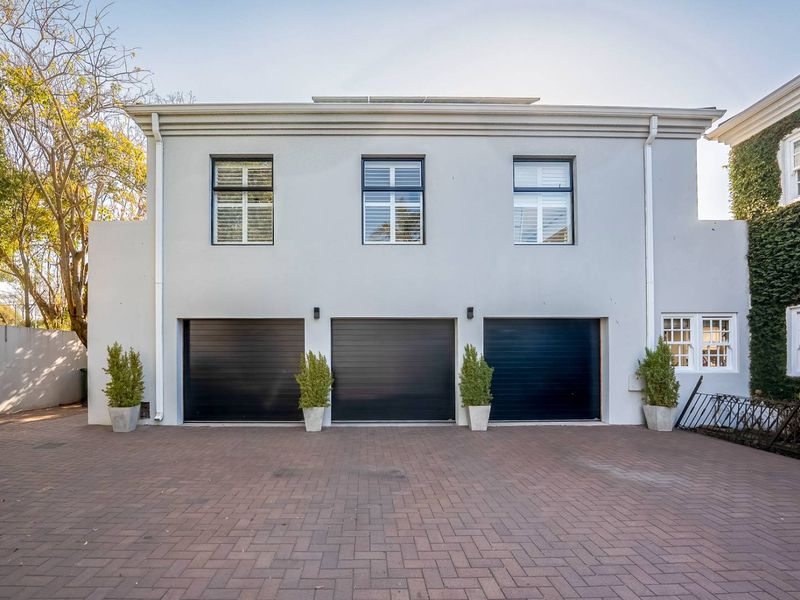 A well-maintained exterior view of a triple garage with a paved driveway and modern grey facade.