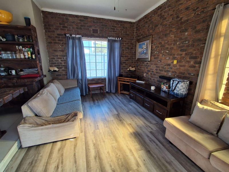 A cozy living room featuring rustic exposed brick walls and modern laminate flooring, providing a warm and inviting atmosphere.