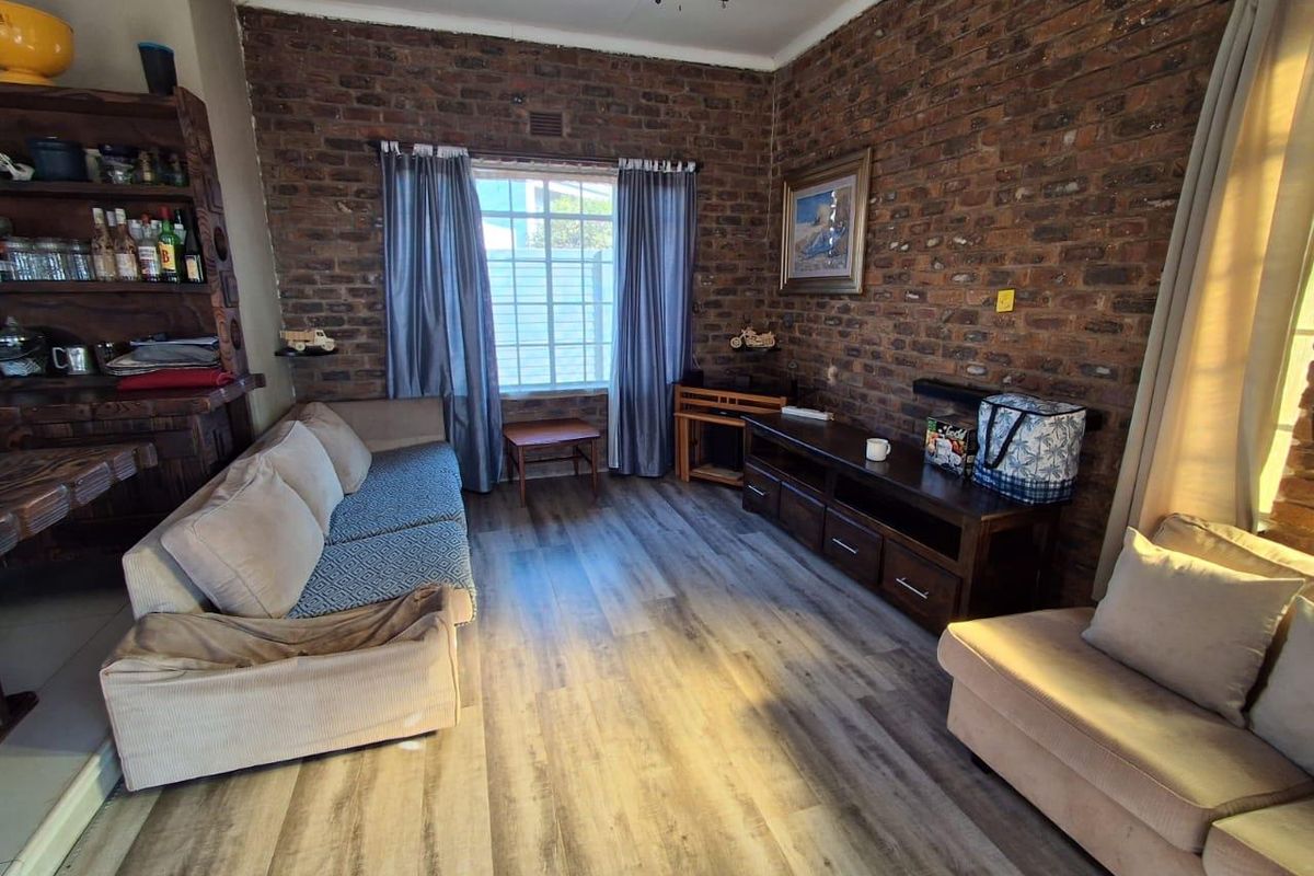 A cozy living room featuring rustic exposed brick walls and modern laminate flooring, providing a warm and inviting atmosphere.