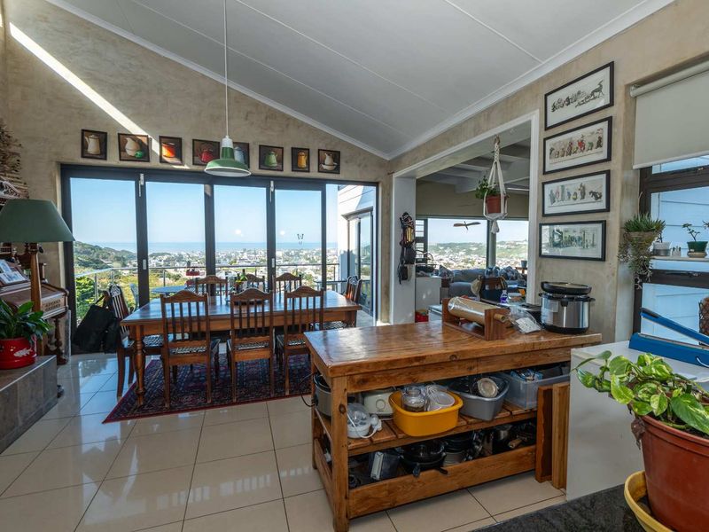Spacious open-plan living and dining area featuring vaulted ceilings, large sliding glass doors, and expansive coastal views.