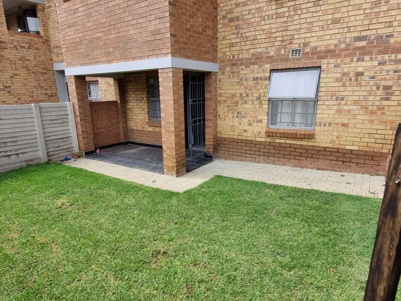 A private rear garden featuring a paved patio area, face brick exterior, and secure boundary walling.