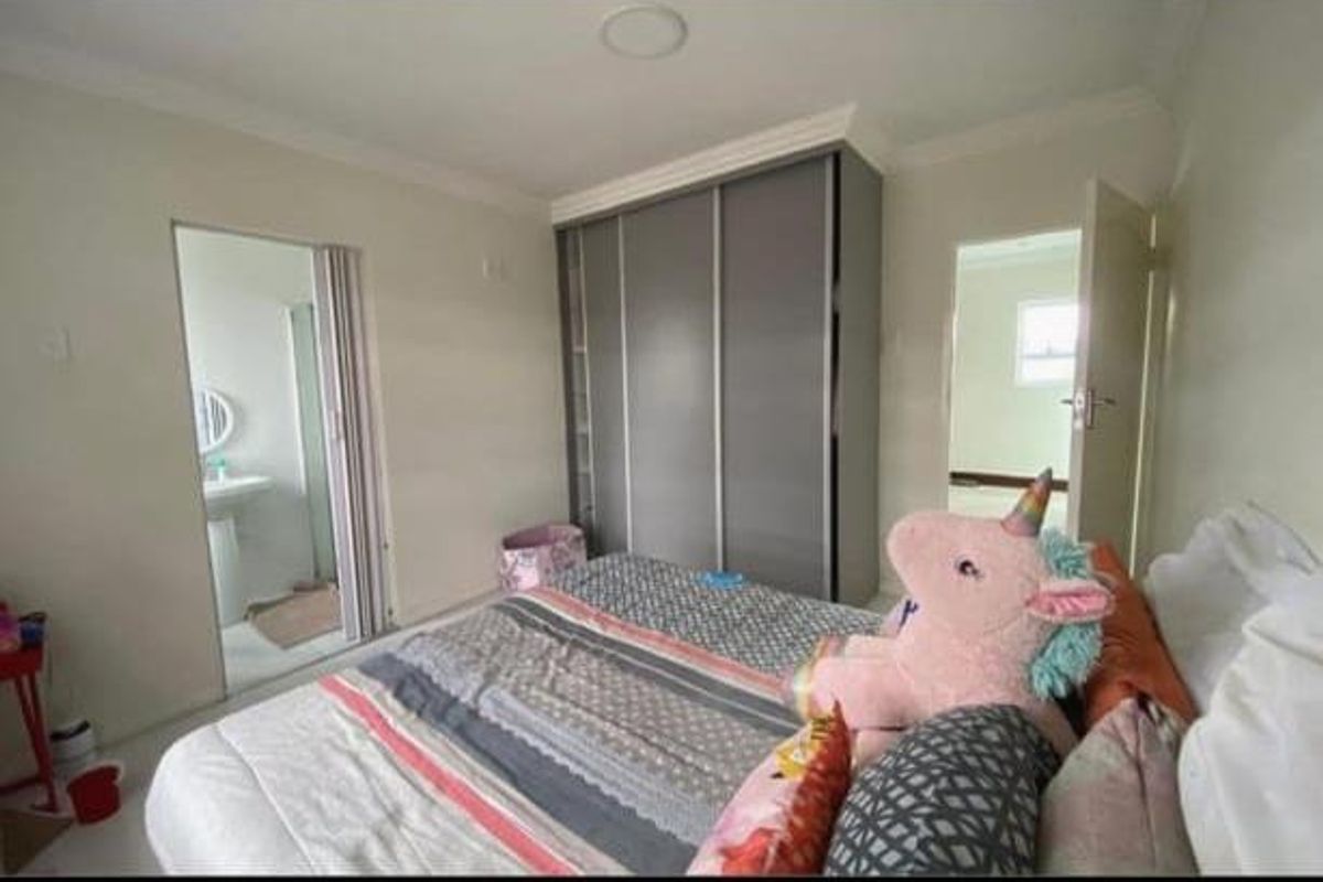 A well-maintained bedroom featuring built-in sliding door wardrobes and an en-suite bathroom with a pedestal sink.